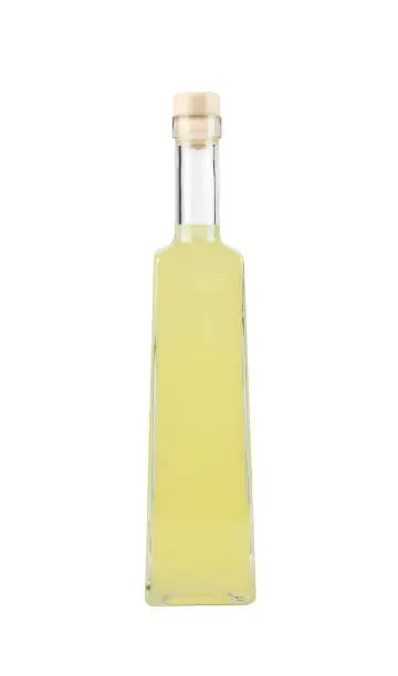 Photo of Limoncello or limoncino is an Italian lemon liqueur, yellow alcoholic drink in tall glass bottle, isolated on white.