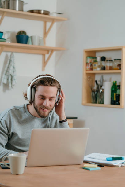 jeune homme utilisant son ordinateur portatif - beautiful indoors looking at camera cheerful photos et images de collection