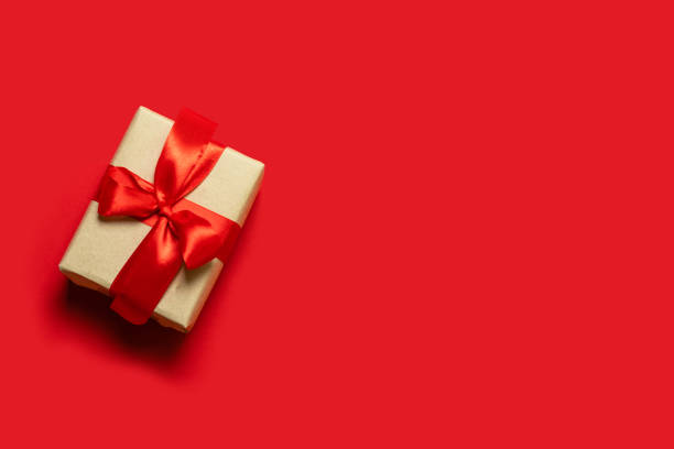 istock Christmas present. Creative banner with craft box and red ribbon on a red background. 1178099474