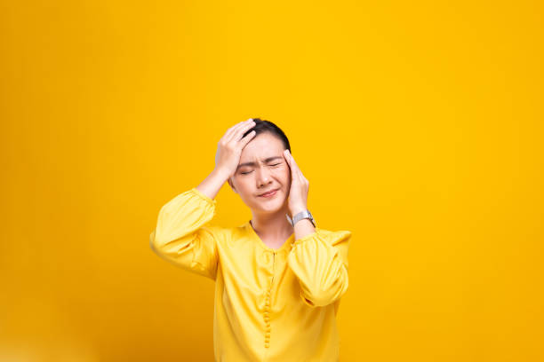 istock Woman has headache isolated over yellow background 1178100296