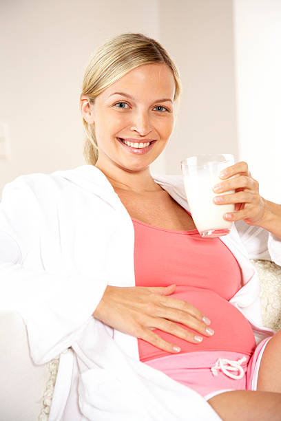 беременная молодая женщина пьет молоко - umfang стоковые фото и изображения
