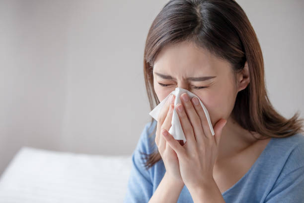 woman has running nose asian woman sick and sneeze with tissue paper in the bedroom sneezing photos stock pictures, royalty-free photos & images