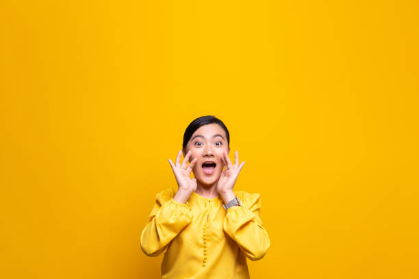 mujer feliz haciendo gesto de grito aislado sobre el fondo amarillo - alardear fotografías e imágenes de stock