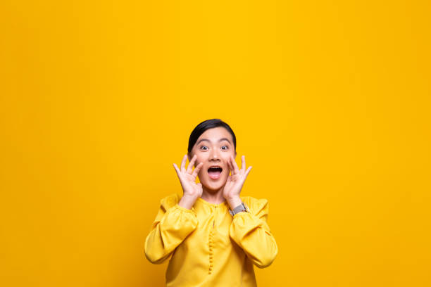Happy woman making shout gesture isolated over yellow background Happy woman making shout gesture isolated over yellow background showing off stock pictures, royalty-free photos & images