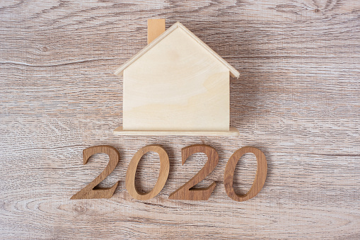 2020 Feliz Año Nuevo con modelo de casa sobre fondo de mesa de madera con espacio de copia. Concepto financiero, monetario, refinanciado, inmobiliario y nuevo concepto de perfeccionamiento photo