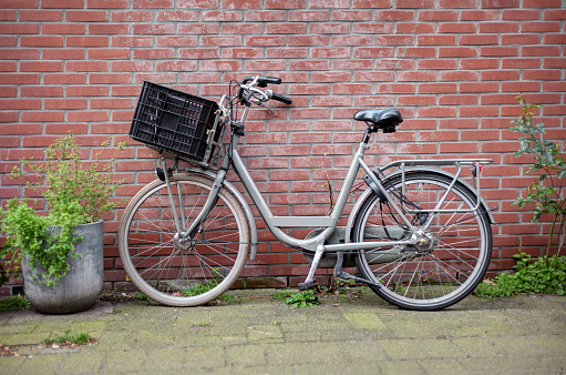 Retro bicycle with a basket standing near old brick wall