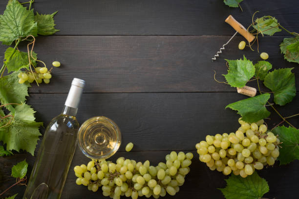bottle of white wine with wineglass, border of ripe grape on wooden table. - wine glass white wine wineglass imagens e fotografias de stock