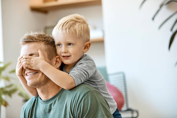 sonriendo lindo chico rubio cubriendo los ojos de padre - oresund escandinavia fotografías e imágenes de stock