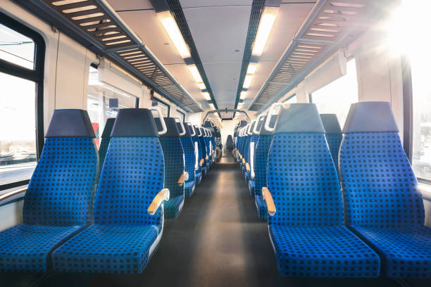 German train interior with two rows of empty seats and sunlight Modern train interior with two rows of blue chairs with the sun coming on the window. German train interior. Eco-friendly public transport. train interior stock pictures, royalty-free photos & images