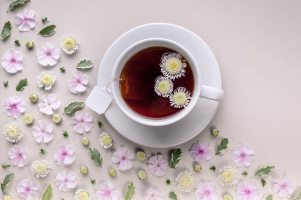 istock Flavored herbal tea in a white ceramic cup with a saucer. Floral pattern on a beige background. Flower tea concept. Tea bag. Copy space 1178114691