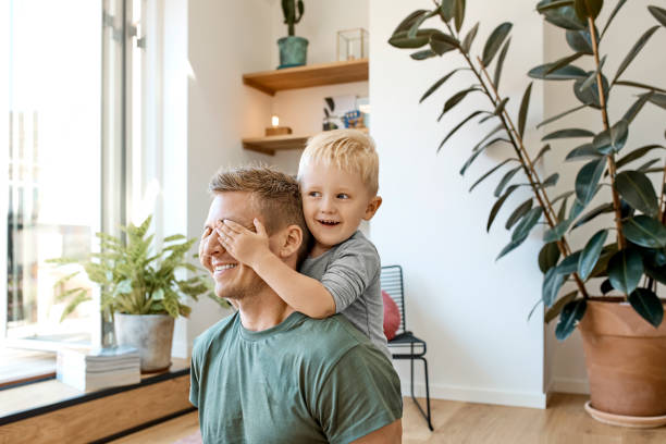 ragazzo sorridente in età prescolare che copre gli occhi del padre - scandinavia foto e immagini stock