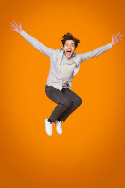 istock Crazy man jumping with raised arms over orange background 1178121239