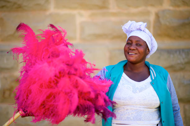 Ostrich Feather Seller looking at camera smiling Friendly African woman portrait selling Ostrich Feather Multi coloured vibrant Dusters in Oudtshoorn Klein Karoo South Africa ostrich farm stock pictures, royalty-free photos & images