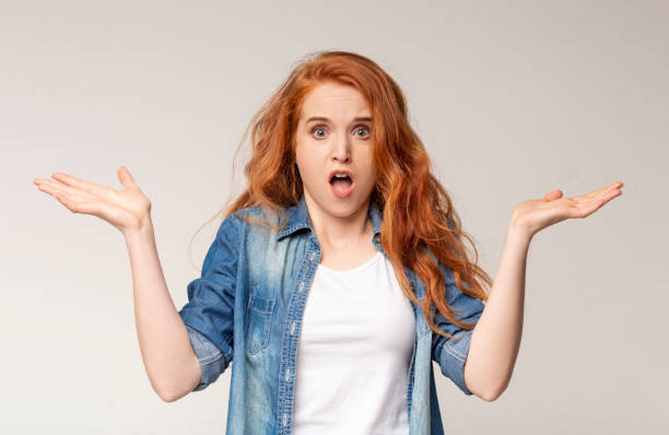 istock Confused Redhead Girl Shrugging Shoulders On Light Studio Background. 1178126767
