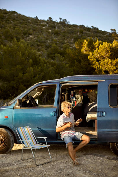 istock Man playing guitar in doorway of van 1178129882