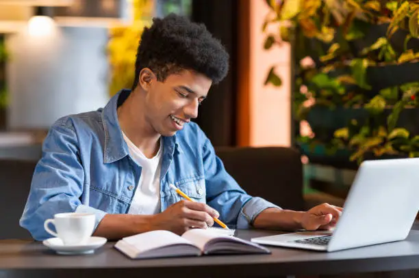 Photo of Successful african student working on project at cafeteria