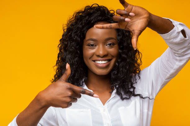 Smiling african woman framing face with fingers