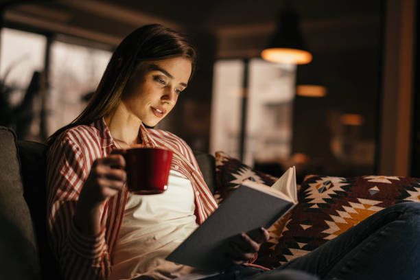 jeune femme affichant le livre - in the evening photos et images de collection