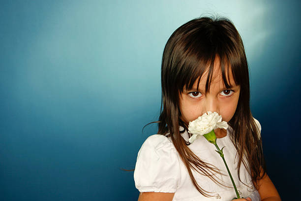 Little girl in white dress holding bouquet of white lilac flowers standing in spring blossom garden looking away