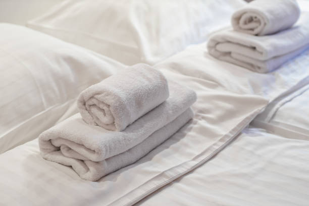 istock Close-up of rolled towels lying on the bed. White sheets. 1178148722