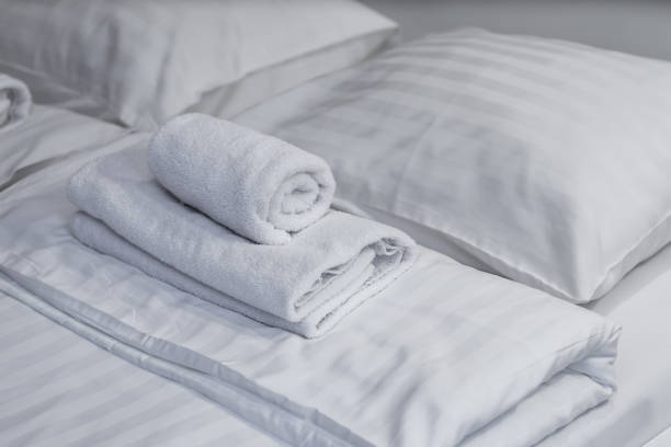 plan rapproché des serviettes roulées se trouvant sur le lit. des draps blancs. - roll away bed photos et images de collection