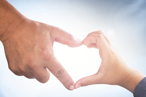 Father and son hand in heart shape on blurred nature background