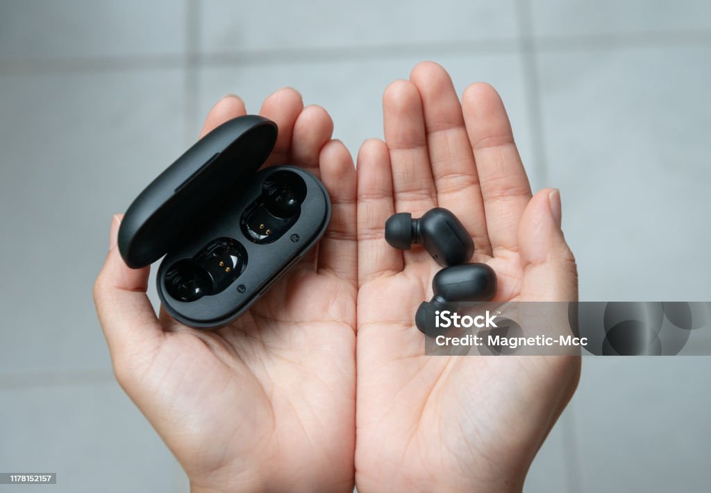 Close up of woman is holding the black true wireless earbuds case in hand Wireless Headphones Stock Photo