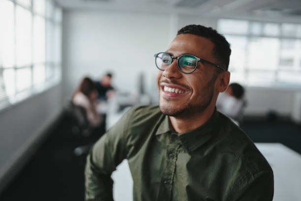 verticale d'un homme d'affaires occasionnel beau utilisant des lunettes noires dans le sourire de bureau - portrait thinking pensive contemplation photos et images de collection