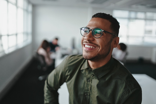 Smiling young businessman looking away at office