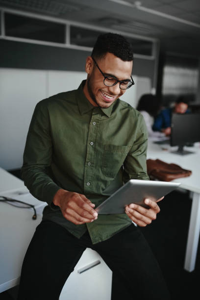 istock Smiling young businessman working online on digital tablet while sitting on desk in a office 1178153698