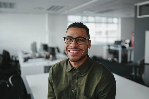 jeune homme d'affaires professionnel américain africain amical et souriant regardant l'appareil-photo dans le bureau moderne - planning business person clothing well dressed photos et images de collection