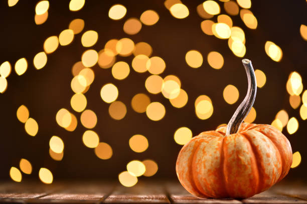 Thanksgiving still life with a pumpkin and illuminated background on a rustic wooden table