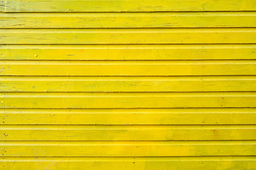 This is a close up photograph of the exterior wall of a yellow painted wooden hut on St. James Beach in Cape Town, South Africa.