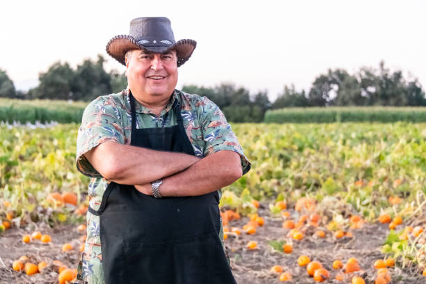 Smiling hispanic mature proud farmer posing at his pumpkin patch ranch