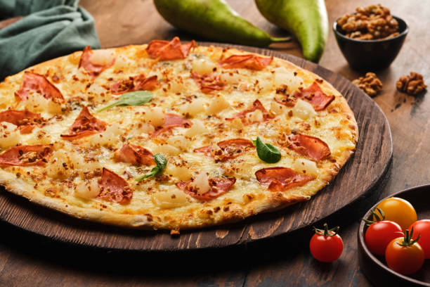 istock Tasty freshly prepared pizza with pear, nuts and bacon on a wooden board, rustic style 1178161645