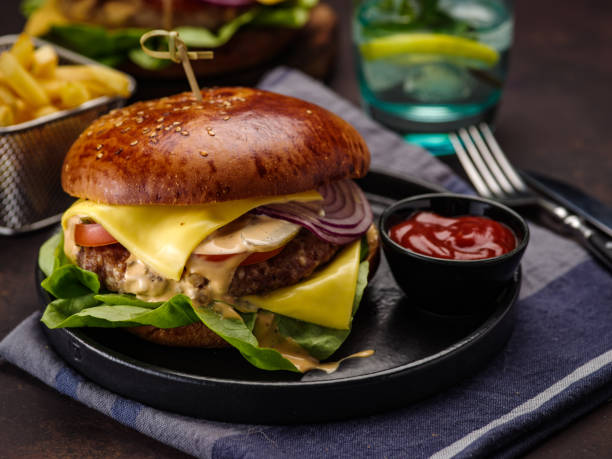 istock Big beef burger with onions and tomatoes. Juicy cheeseburger on a dark table 1178161716