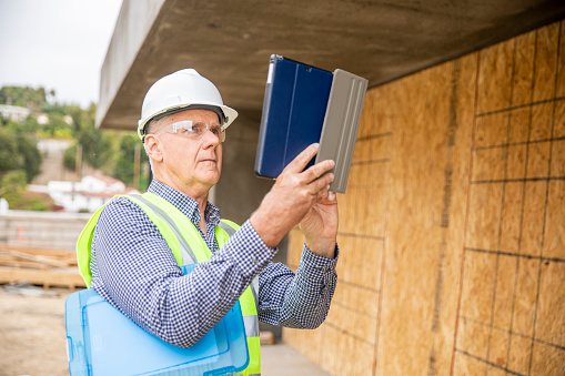 A senior construction site manager visually inspects a building project