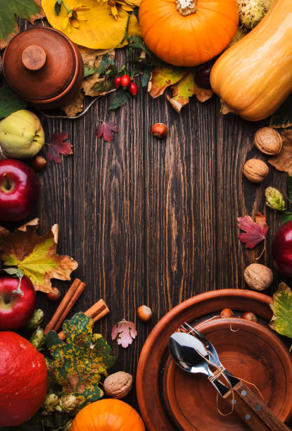 Thanksgiving dinner place setting. Autumn fruit, pumpkins, nuts, fallen leaves with plate and cutlery. Thanksgiving autumn background