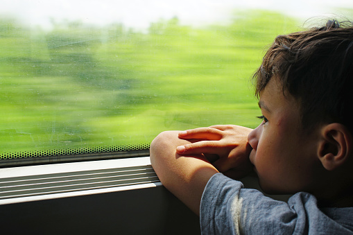 A head shot of a boy watching scenery by the window in a train traveling through Transilvania, Romania