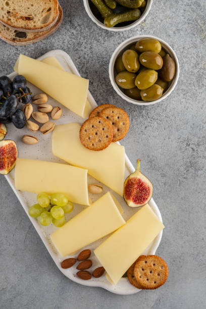 istock Cheese slices on white board with honey, figs, olives, grapes. 1178166520