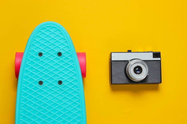 istock Retro set with blue skateboard and retro camera on yellow background. Studio shot. Youth lifestyle. Top view 1178169971