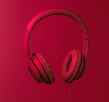 Classic wired headphones with red neon light. Retro style. Minimalistic music concept.