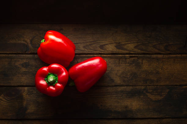 rote paprika auf dunklem holzhintergrund - green bell pepper bell pepper red bell pepper groceries stock-fotos und bilder