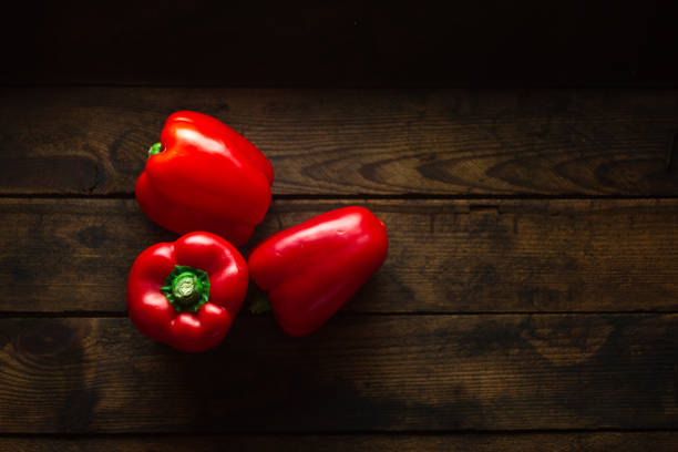 pimienta de campana roja sobre fondo de madera oscura - pepper vegetable bell pepper red bell pepper fotografías e imágenes de stock