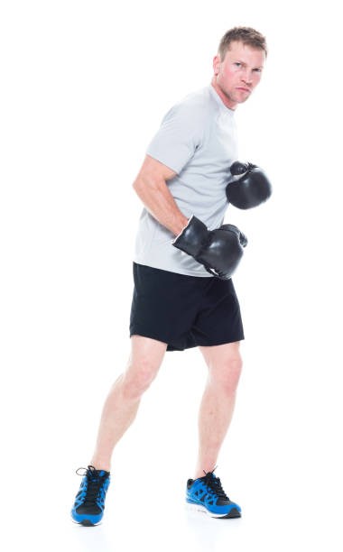 full length / one man only / one person / front view of 20-29 years old handsome people brown hair / short hair caucasian male / young men athlete / sportsperson standing in front of white background and boxing / showing fist / sport - beautiful men young adult 25 30 years imagens e fotografias de stock