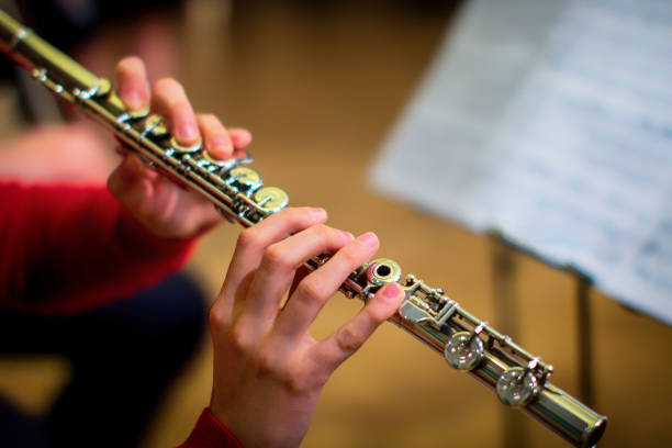 la jeune fille tient une grande flûte de concert (dans les mains en gros plan). musicien professionnel à la répétition. une femme joue de la flûte transversale. - flûte traversière photos et images de collection