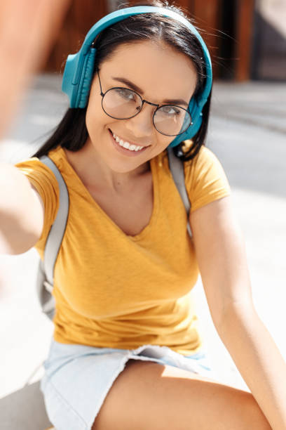 zabawna brunetka młoda kobieta z jasnym uśmiechem ubrana w swobodne ubrania robi selfie ze smartfonem na ulicy. - skirt women jeans white zdjęcia i obrazy z banku zdjęć