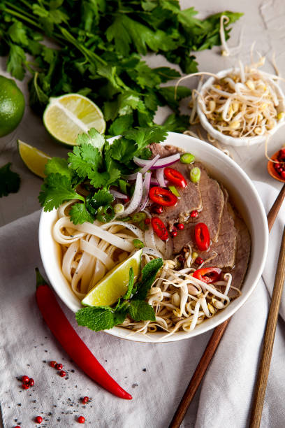 Pho Noodle Soup on dark table. Beef with Chilli, Basil, Rice Noodles, Bean Shoots showing noodles