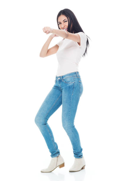 full length / one person / front view of 20-29 years old adult beautiful / long hair latin american and hispanic ethnicity female / young women standing in front of white background wearing jeans / t-shirt / shirt who is serious / cool attitude - fighting stance imagens e fotografias de stock