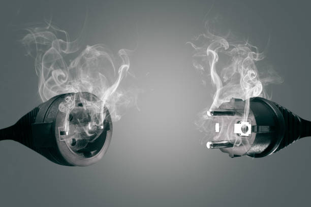 Smoking power plug and socket A European electric plug and socket in front of a grey background. Both objects are covered by white smoke. blackout photos stock pictures, royalty-free photos & images